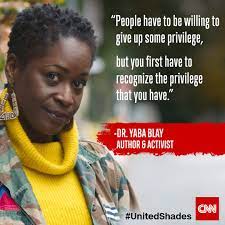 
The image features a woman with short, natural hair and a vibrant yellow sweater standing outdoors. To her right, there's a quote attributed to Dr. Yaba Blay, which reads: "People have to be willing to give up some privilege, but you first have to recognize the privilege that you have." 