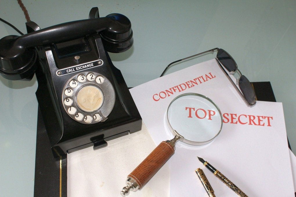 Confidential files on desk with phone and magnifying glass