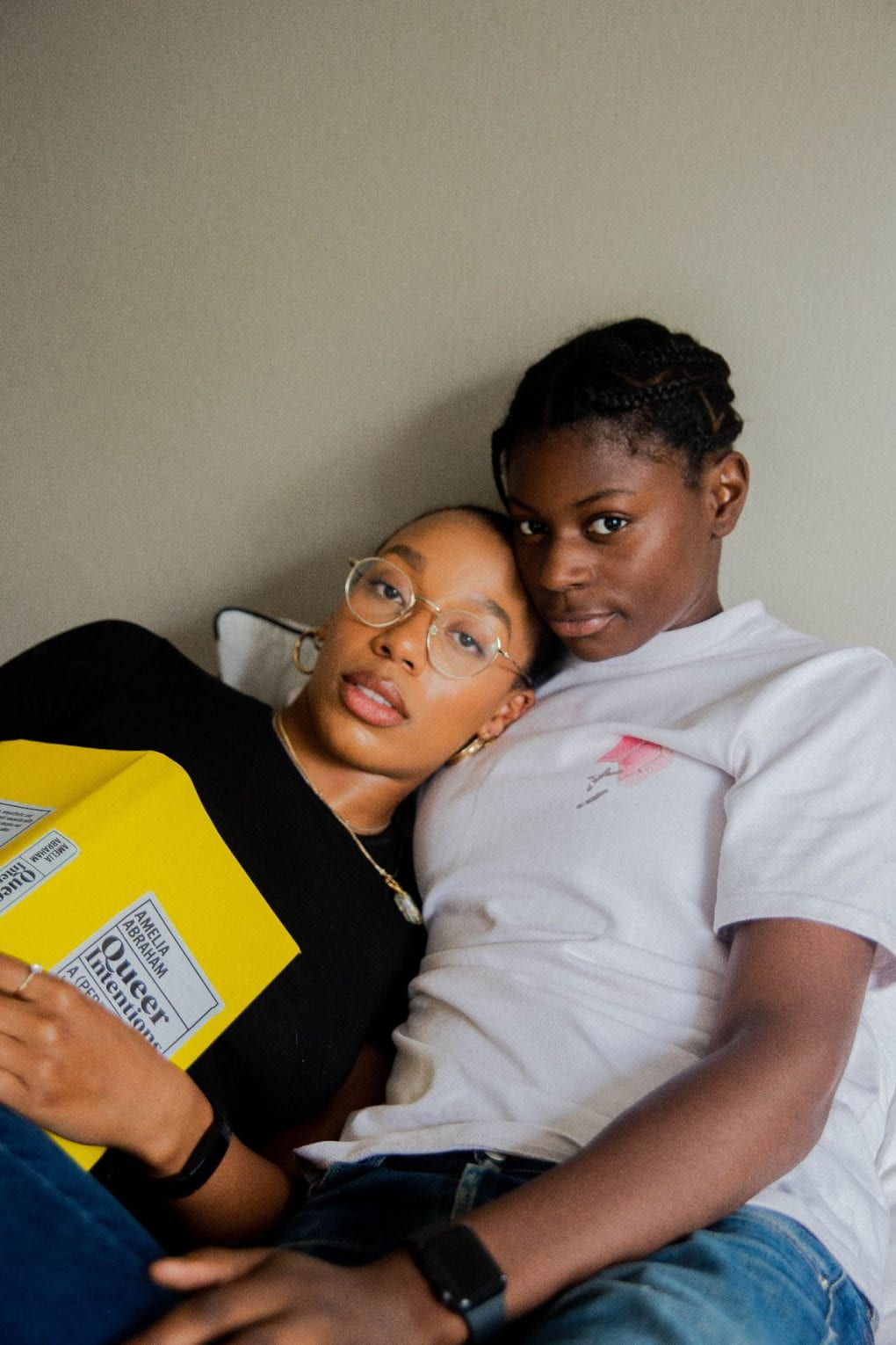 Two women reclining with a book titled Queer Intentions.