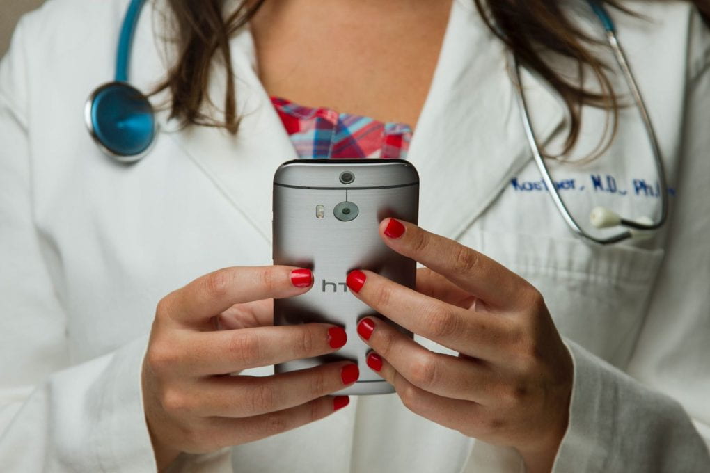 Close up of woman with stethoscope holding a smartphone