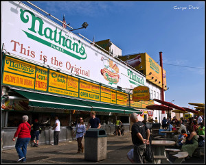 Nathan's Famous Hot Dog stand is located just below the Coney Island boardwalk. Source: http://bookroomsnow.com/get-packin/tag/4th-of-july-celebrations/