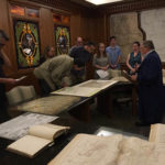 group of men and women viewing maps and books spread out on a large conference table