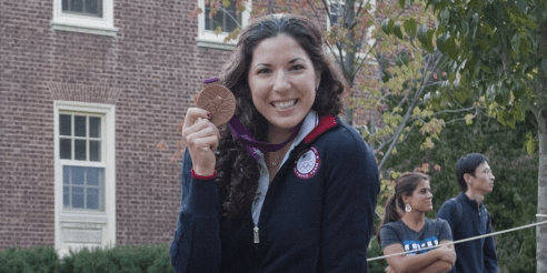 Natalie Dell holding her bronze medal and smiling for the camera during the Homecoming Parade.