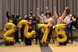 Masked students hold balloons with the number 2275 to celebrate their fundraising accomplishment