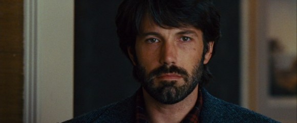 As CIA agent Tony Mendez, Ben Affleck gazes meaningfully back at the six diplomats he is trying to rescue.  Still from DVD of Argo, directed by Ben Affleck, produced by Warner Brothers.