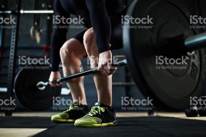 Active young man training with barbell in gym