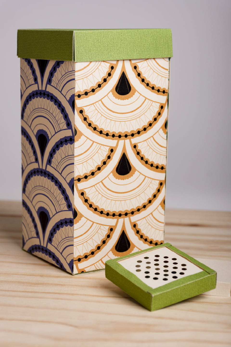 Packaging design for matcha. One large green patterend box that pulls up to show smaller, individual packages of matcha. The lid of these smaller packages is perforated.
